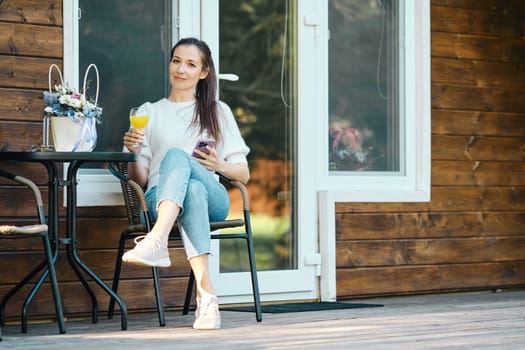Cheerful woman relaxing on wooden cottage on the terrace in nature