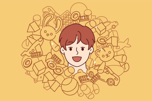 Face of teenager boy among toys and constructor for entertainment or development of child. Cheerful boy from kindergarten laughing enjoying happy childhood and abundance of toys for spending time