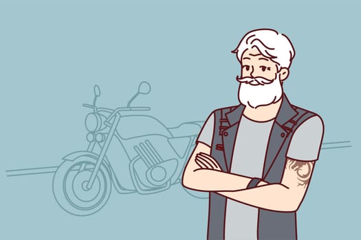 Old biker near motorcycle wishes to travel after retirement. Confident old man with tattoo on arms and gray hair is wearing biker vest for traveling around city or country on motorcycle