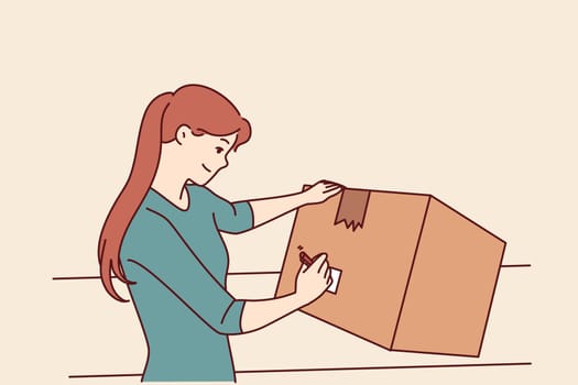 Woman with cardboard box signs package before sending goods through postal service or courier company. Young girl with big box packs household items when moving or renovating apartment
