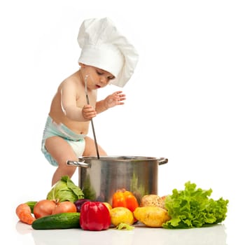 Little boy in chef's hat with ladle, casserole, and vegetables on white background