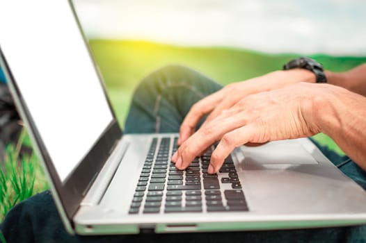 Close up of person hands on the laptop keyboard outdoors, Close-up of a man's hands working on his laptop. Side view of hands working on laptop