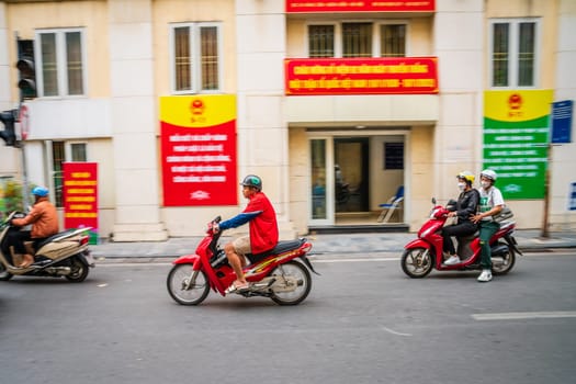 Hanoi, Vietnam, November 15, 2022: Scooters are passing by a party office buiding in French Quarter of Hanoi