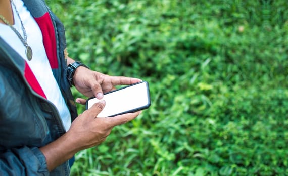 Close up of a man with cell phone in hand, close up of hands with cell phone with white screen, young guy with cell phone in hand with copy space