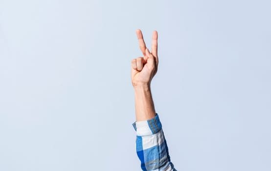 Hand gesturing the letter K in sign language on an isolated background. Man's hand gesturing the letter K of the alphabet isolated. Letters of the alphabet in sign language