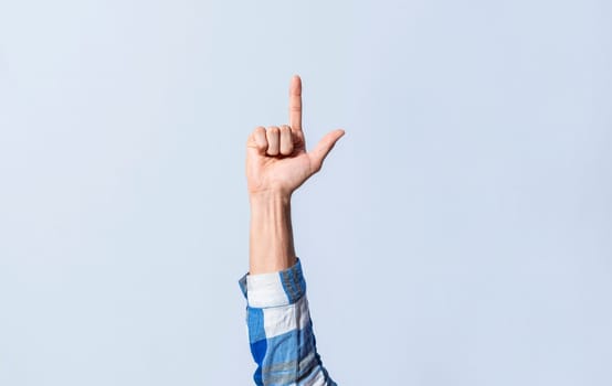 Hand gesturing the letter L in sign language on an isolated background. Man's hand gesturing the letter L of the alphabet isolated. Letters of the alphabet in sign language