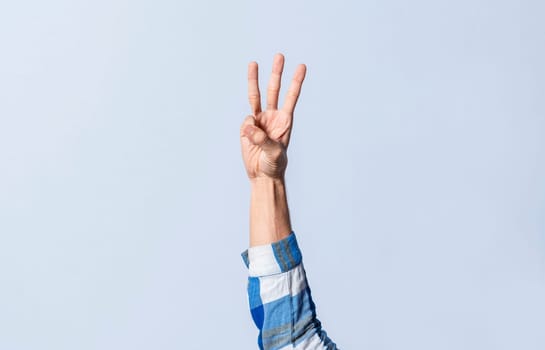 Hand gesturing the letter W in sign language on an isolated background. Man's hand gesturing the letter W of the alphabet isolated. Letter W of the alphabet in sign language