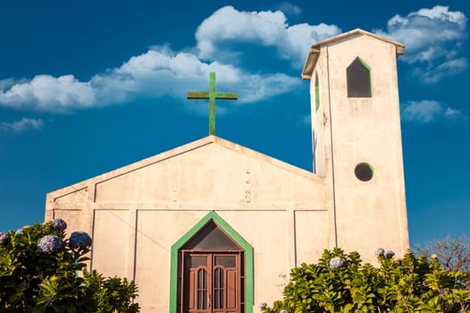 Front view of the entrance of a church, view of the entrance of a church with the cross on the roof