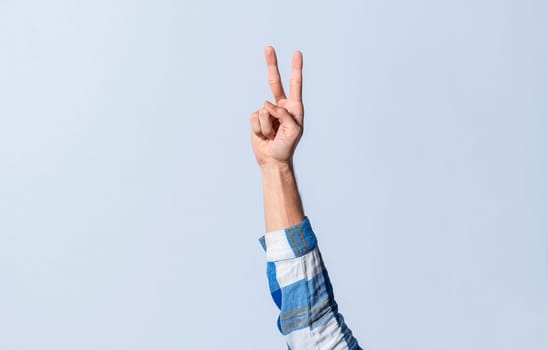 Hand gesturing the letter V in sign language on an isolated background. Man's hand gesturing the letter V of the alphabet isolated. Letter V of the alphabet in sign language