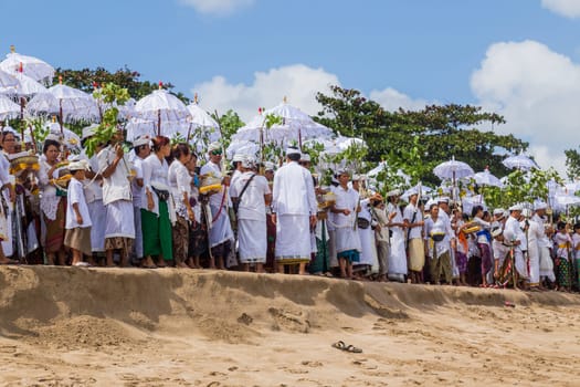 Bali, Indonesia: 17 August 2020: People during Melasti Ritual. Ceremony is held on the edge of the beach with the aim to purify oneself of all the bad things in the past and throw it to ocean.