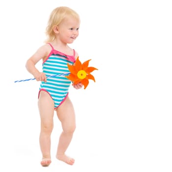 Happy baby in swimsuit with pinwheel looking on copy space