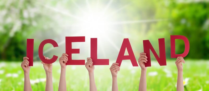 People Or Persons Hands Building English Word Iceland. Sunny Green Grass Meadow As Background.