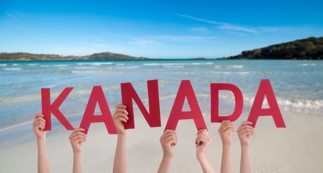 People Or Persons Hands Building German Word Kanada Means Canada. Summer Ocean, Sea And Beach As Background.