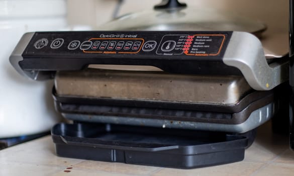 Dirty electric grill with a closed lid. Dirty electric stove in the home kitchen. Stainless steel household cooking appliance. healthy food. food without oil and fat