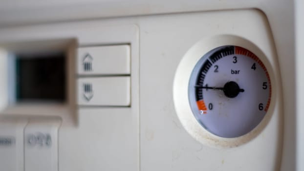 Gas pressure meter on the panel of the heating gas boiler. Symbolic image of the heating season at home. Dial and pressure gauge on combi boiler. Hot water and heating. Boiler accessories