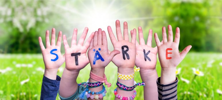 Children Hands Building Colorful German Word Staerke Means Strength. Sunny Green Grass Meadow As Background.