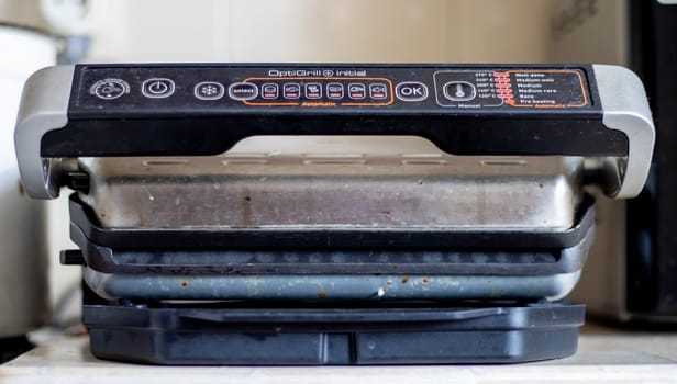 Dirty electric grill with a closed lid. Dirty electric stove in the home kitchen. Stainless steel household cooking appliance. healthy food. food without oil and fat