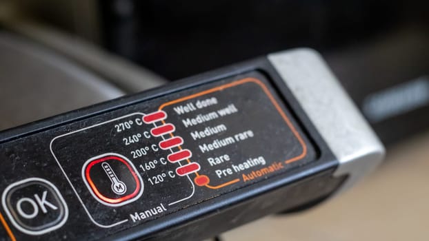 Electric grill power adjustment indicators and power button. The degree of doneness of the steak. Contact grill. Cooking in the home kitchen