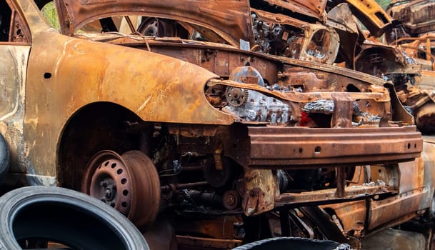 A lot of burnt fired cars in the parking lot, the consequences of the invasion of Ukraine. War in Ukraine. Cemetery of destroyed cars of civilians who tried to evacuate from the war zone