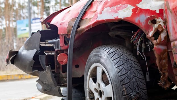 Broken rumpled red car after a severe accident with a skewed body, after a powerful blow. Accident on the street, damaged car after a collision in the city. Auto accident. Broken car on the street