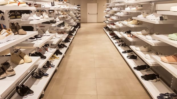 Large collection of different shoes. Shop for men's, women's and children's shoes. Background with shoes on the shelves inside the store. Very large selection of shoes