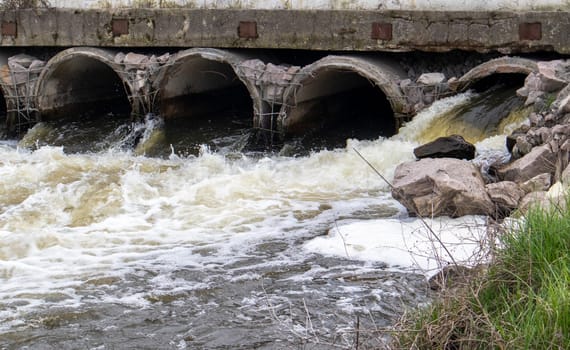 A concrete pipe that carries smelly, polluted sewage into the river through pipes. Pollution of the environment and water bodies. Ecological catastrophy. Hazardous waste water