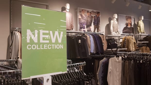 A sign in a men's clothing store with a sign NEW COLLECTION with light highlights. Conceptual luxury store, mall, store sale, retail store, outlet. Ukraine, Kyiv - May 23, 2022