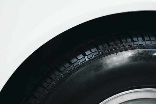 front view detail of car wheel black rubber tire on the front wing fender of white car