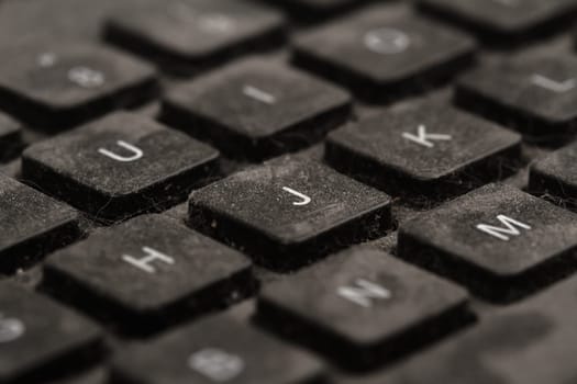 front view closeup of old black keyboard with keys covered in dust and dirt isolated on white background