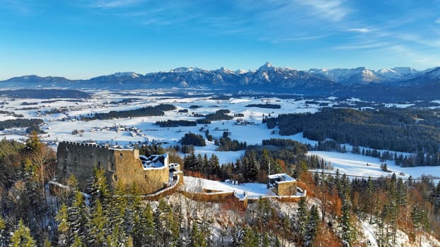 Drohnenaufnahme von der Ruine Burg Eisenberg vor den Allgäuer Alpen im Winter