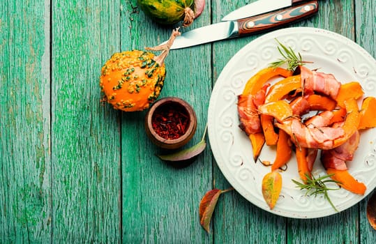Autumn baked pumpkin pieces wrapped in bacon. Thanksgiving Day