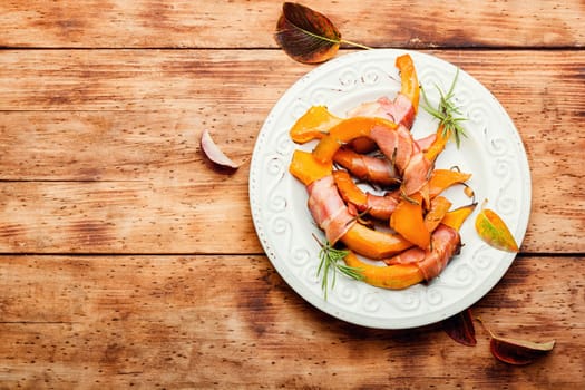 Autumn baked pumpkin pieces wrapped in bacon. Thanksgiving Day