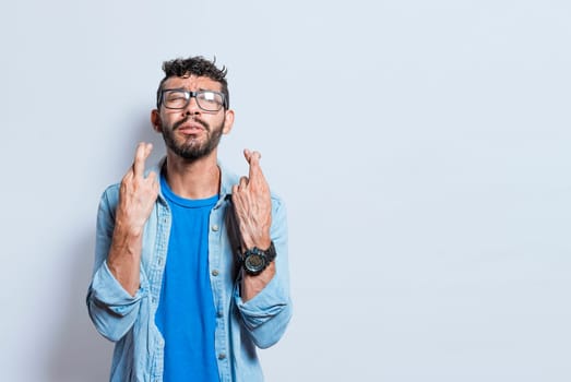 Worried person crossing his fingers making a wish, concerned man apologizing, hopeful man asking for help or apologizing, superstitious man crossing his fingers asking for something