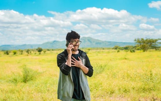 Smiling man calling on the phone on the field, people talking on the cell phone in the field. Man calling on the phone in the field, A man in a beautiful field talking on the phone
