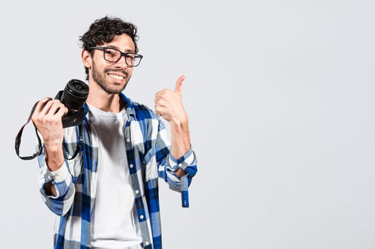 Smiling male photographer showing a camera and giving thumb up. Young man holding a camera and giving the thumb up, Smiling guy photographer showing a camera with thumb ok