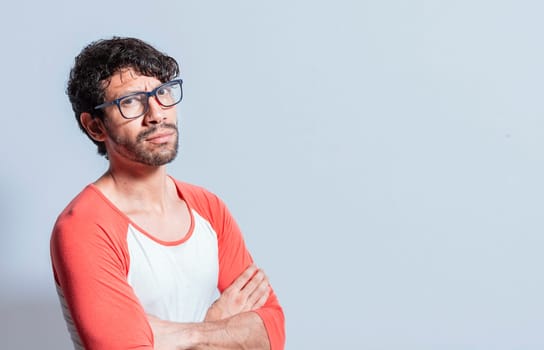 Young latin man in glasses with crossed arms looking in profile at the camera. Nicaraguan man with crossed arms looking at the camera isolated, Portrait of young man with crossed arms isolated