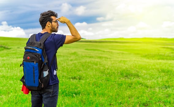 Adventurous man in the field, man with backpack in the field looking