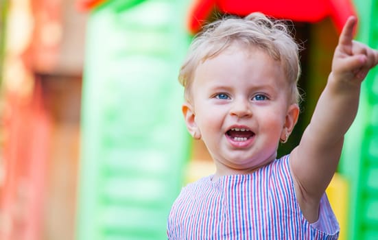 Portrait of 1 year old baby girl pointing her finger, at home in the garden.