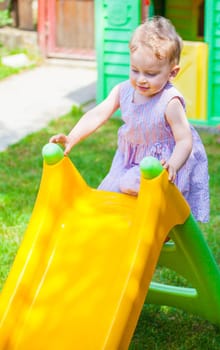Portrait of 1 year old baby girl playing at home with the slide.
