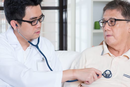 Doctor and patient. Sick Asian elder man consult family doctor, sitting on sofa. Senior retiree indoors living lifestyle.