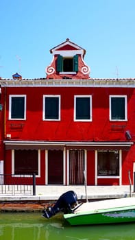Burano red color building architecture and boat in the river, Venice, Italy