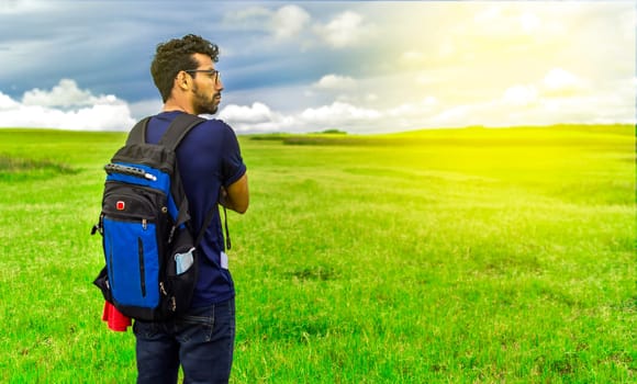 Adventurous man in the field, man with backpack in the field looking