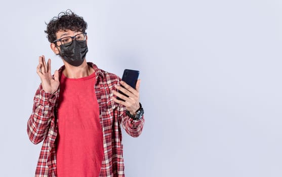 Teen guy with mask making video call from his cell phone, Man with surgical mask making video call isolated, face mask video call concept