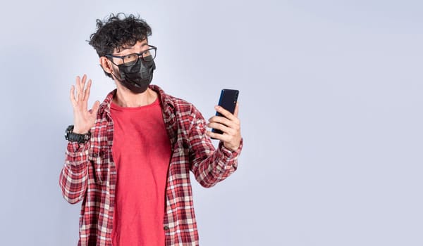 Man with surgical mask making video call isolated, guy with mask making video call from his cell phone, face mask video call concept
