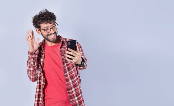 Smiling man making video call with his cellphone isolated, Positive teen guy making video call waving hands, Concept of smiling man saying hello by video call on cellphone