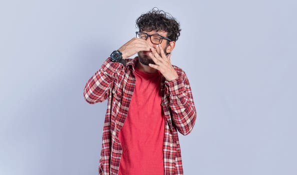 People holding his nose with unpleasant smell expression, Young man with bad smell expression holding his nose. Person holding his nose looking at camera
