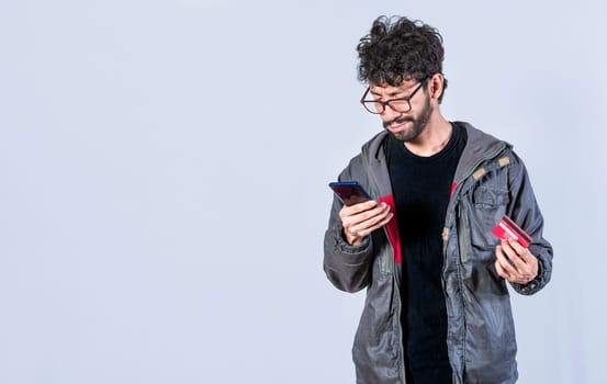 Handsome man paying from his phone with a credit card, Man paying online with a credit card from his cell phone. Happy man paying online with his cell phone and debit card.