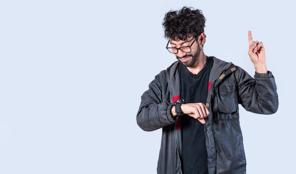Isolated person looking at his watch and raising his finger, A man measuring time with a hand watch, Handsome man looking at the time and raising his finger
