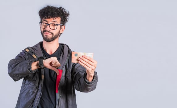 Unhappy person with a Nicaraguan banknote with his thumb down, Concept of a person with money problems. Sad person with a bank note with his thumb down
