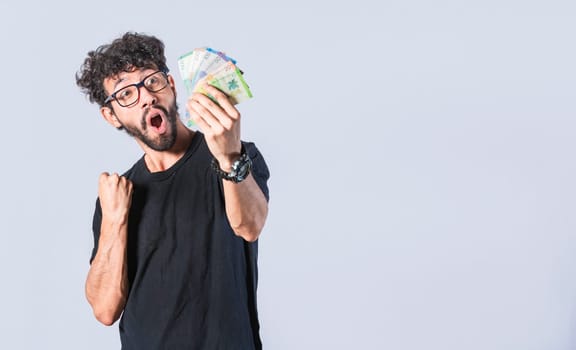 Excited man with money in his hand, astonished man with banknotes in his hand, concept of man earning money